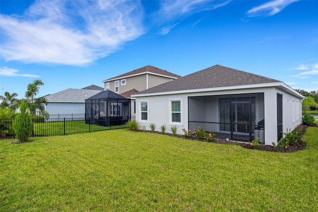 back of property with a sunroom, a lanai, and a lawn