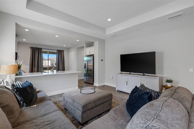 living room featuring a tray ceiling and dark hardwood / wood-style floors