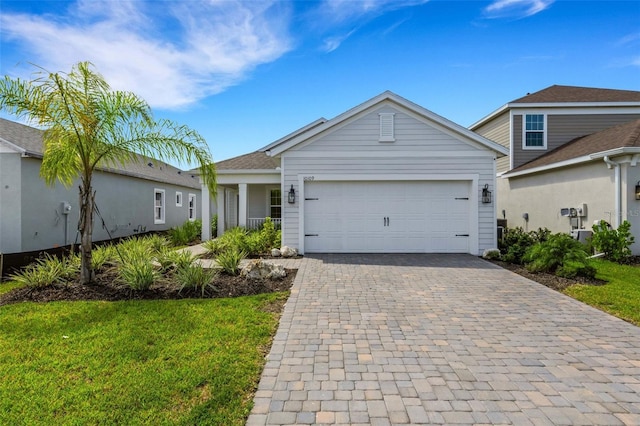 view of front of property featuring a front lawn, decorative driveway, and an attached garage