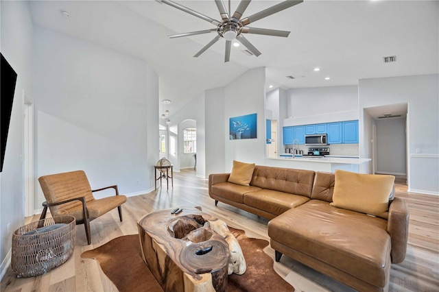 living room with ceiling fan, light hardwood / wood-style floors, and high vaulted ceiling