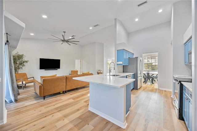 kitchen with ceiling fan, high vaulted ceiling, blue cabinetry, stainless steel appliances, and light wood-type flooring