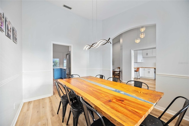 dining space featuring a towering ceiling and light hardwood / wood-style floors