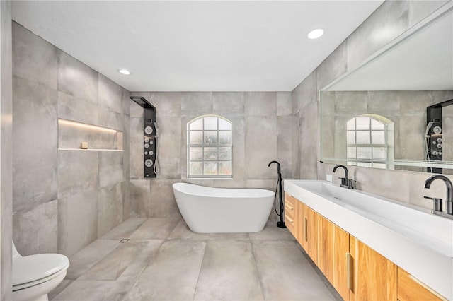 bathroom with tile walls, a wealth of natural light, vanity, and toilet