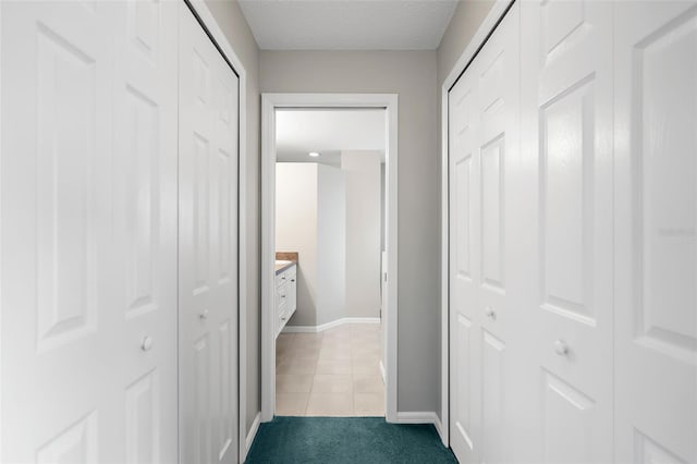 hall with a textured ceiling and light tile patterned floors