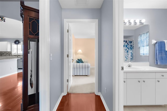 hallway featuring wood-type flooring and sink