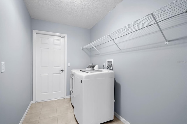 washroom featuring washer and clothes dryer, a textured ceiling, and light tile patterned floors