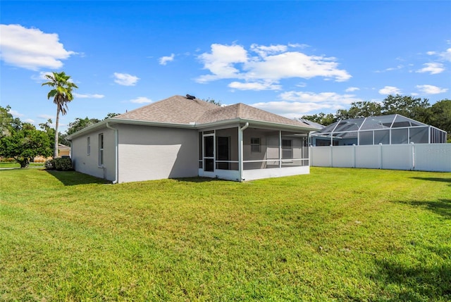 rear view of house featuring a sunroom and a lawn