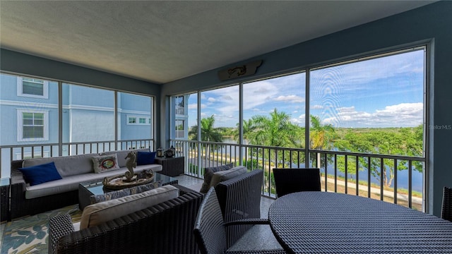 sunroom featuring a water view