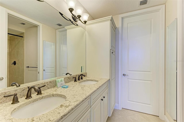 bathroom featuring vanity, a textured ceiling, a chandelier, and tile patterned floors