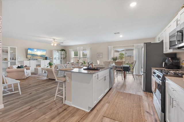 kitchen with stainless steel appliances, sink, light wood-type flooring, and white cabinets