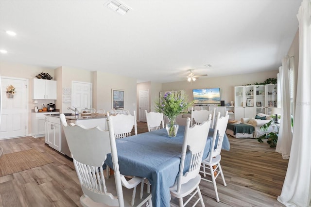 dining area with sink, ceiling fan, and light hardwood / wood-style flooring