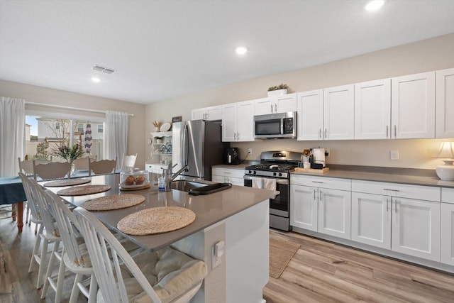 kitchen featuring stainless steel appliances, light hardwood / wood-style flooring, and white cabinets