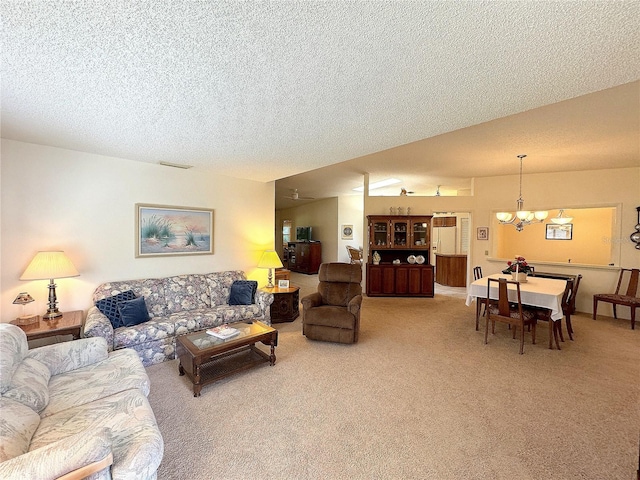 living room with a chandelier, a textured ceiling, and carpet flooring