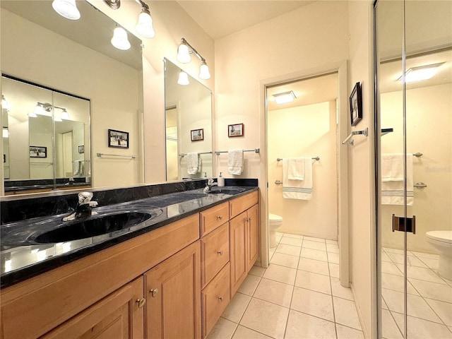 bathroom with a shower with shower door, vanity, toilet, and tile patterned floors