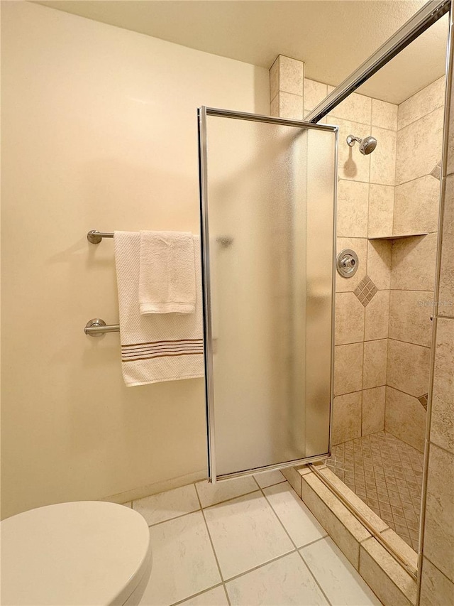 bathroom featuring tile patterned flooring, a shower with door, and toilet