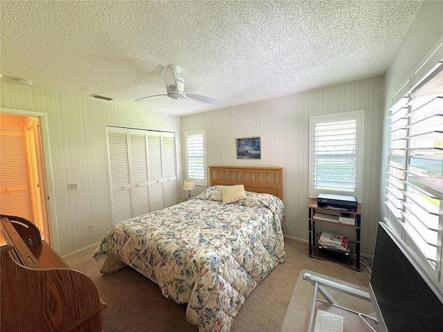 carpeted bedroom with ceiling fan, a textured ceiling, and a closet