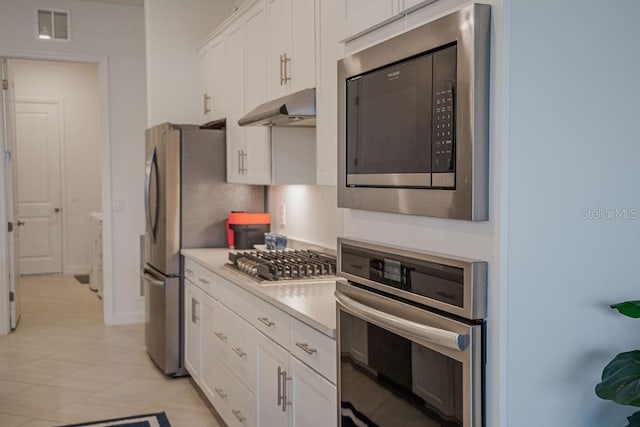 kitchen with white cabinets, light tile patterned floors, and appliances with stainless steel finishes