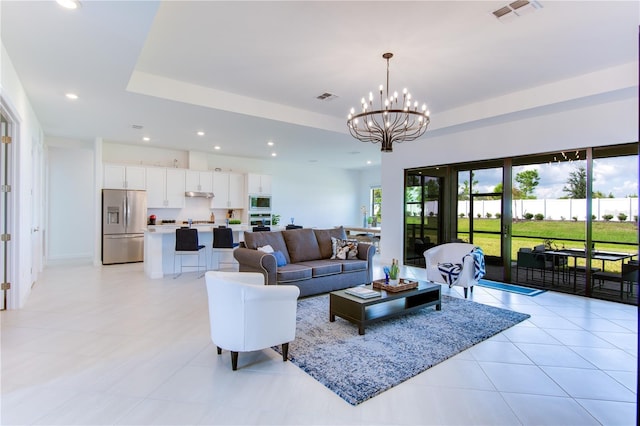 tiled living room with a tray ceiling and a chandelier