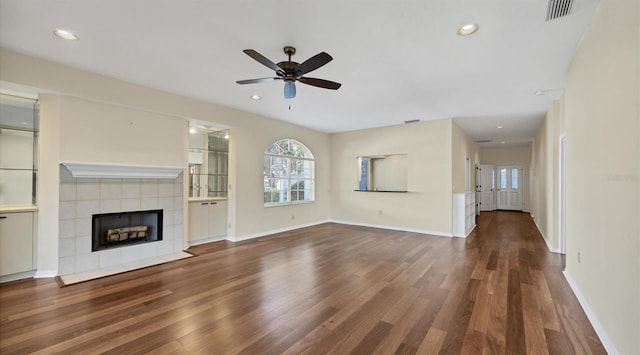 unfurnished living room with wood-type flooring, ceiling fan, and a tiled fireplace