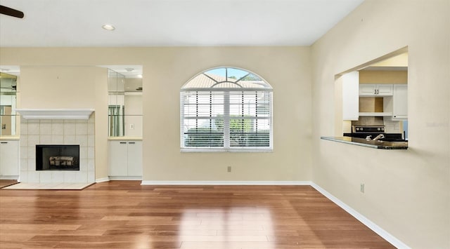 unfurnished living room featuring a tile fireplace and hardwood / wood-style floors