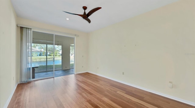 empty room with hardwood / wood-style floors, ceiling fan, and a water view