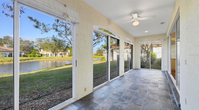 unfurnished sunroom with a water view and ceiling fan