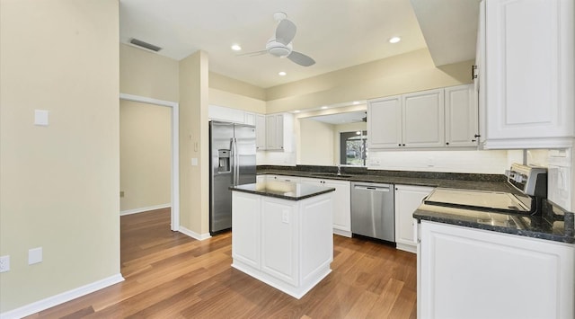 kitchen featuring hardwood / wood-style flooring, a center island, white cabinets, and appliances with stainless steel finishes