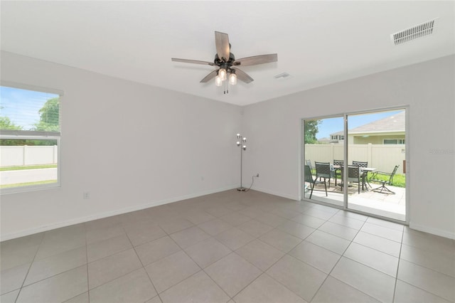 tiled empty room featuring a healthy amount of sunlight and ceiling fan