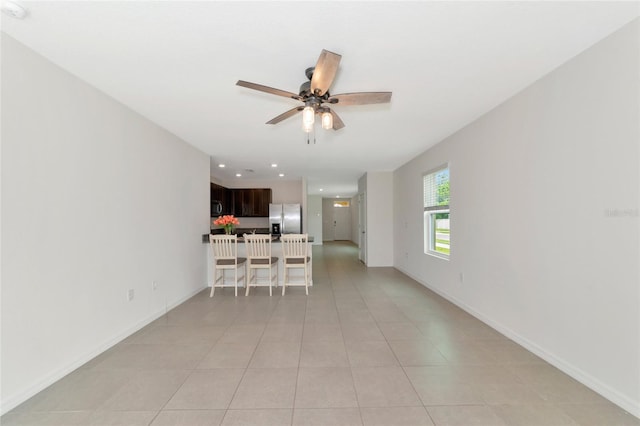 unfurnished living room featuring light tile patterned floors and ceiling fan