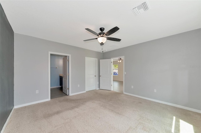 unfurnished bedroom with ceiling fan, light colored carpet, and ensuite bathroom