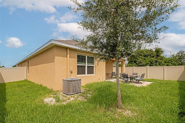 back of house with cooling unit, a lawn, and a patio area