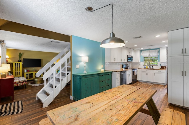 kitchen featuring a textured ceiling, appliances with stainless steel finishes, dark hardwood / wood-style floors, and white cabinetry