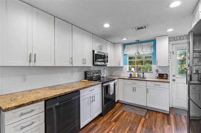 kitchen with light stone counters, a textured ceiling, dark wood-type flooring, white cabinetry, and stainless steel appliances