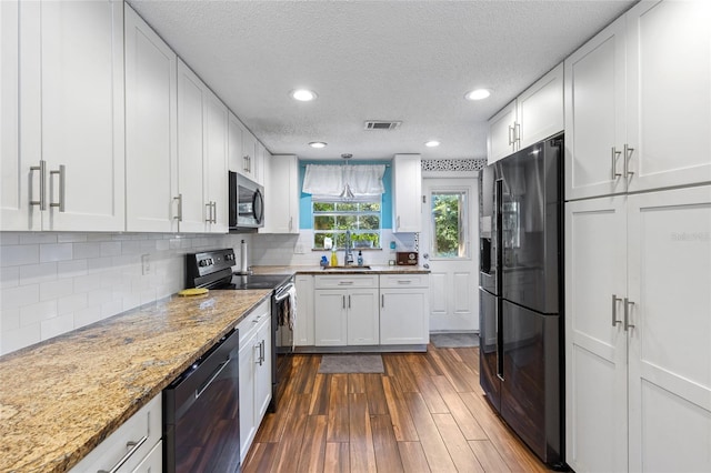 kitchen with a textured ceiling, black appliances, white cabinetry, and dark hardwood / wood-style floors