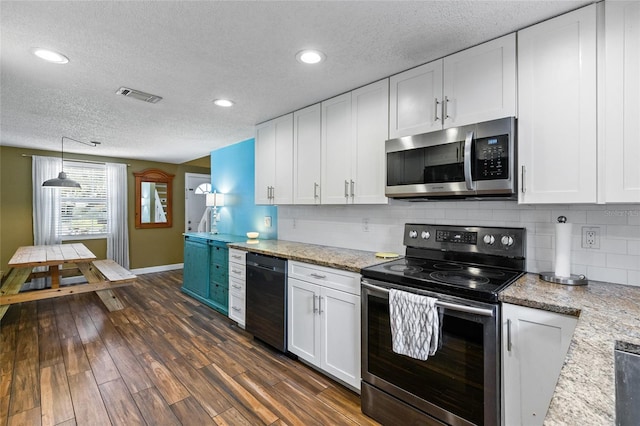 kitchen with dark wood-type flooring, white cabinets, backsplash, stainless steel appliances, and decorative light fixtures