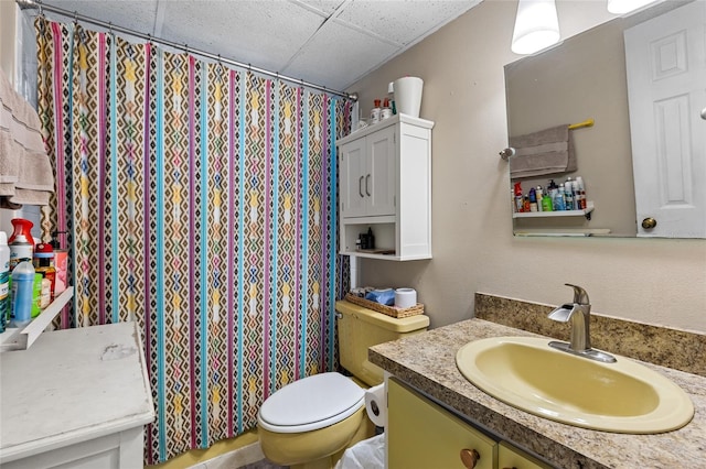 bathroom with walk in shower, vanity, a drop ceiling, and toilet