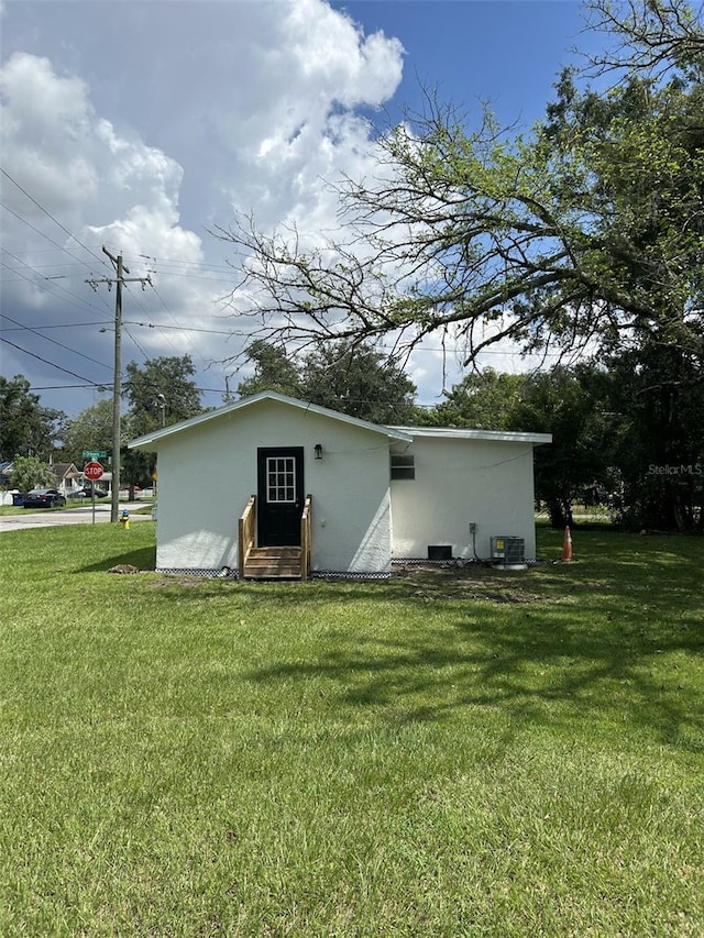 back of property with central AC and a yard