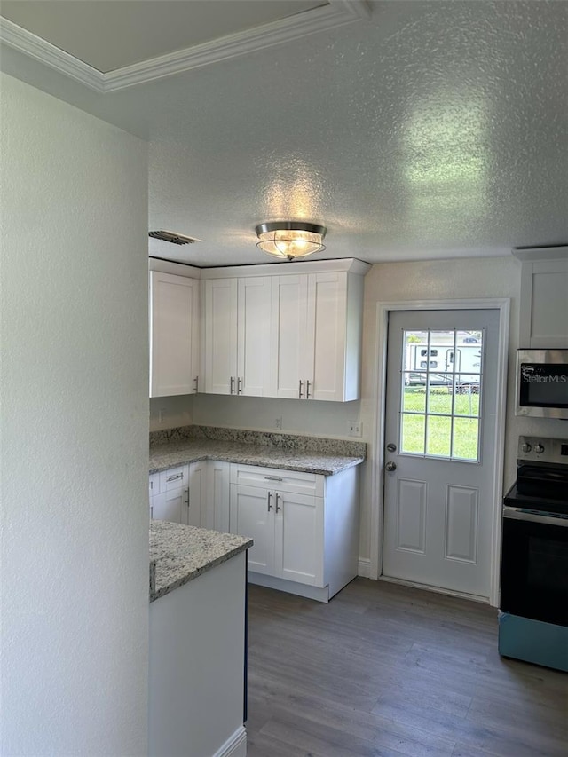 kitchen featuring white cabinetry, light stone counters, stainless steel appliances, crown molding, and light hardwood / wood-style flooring