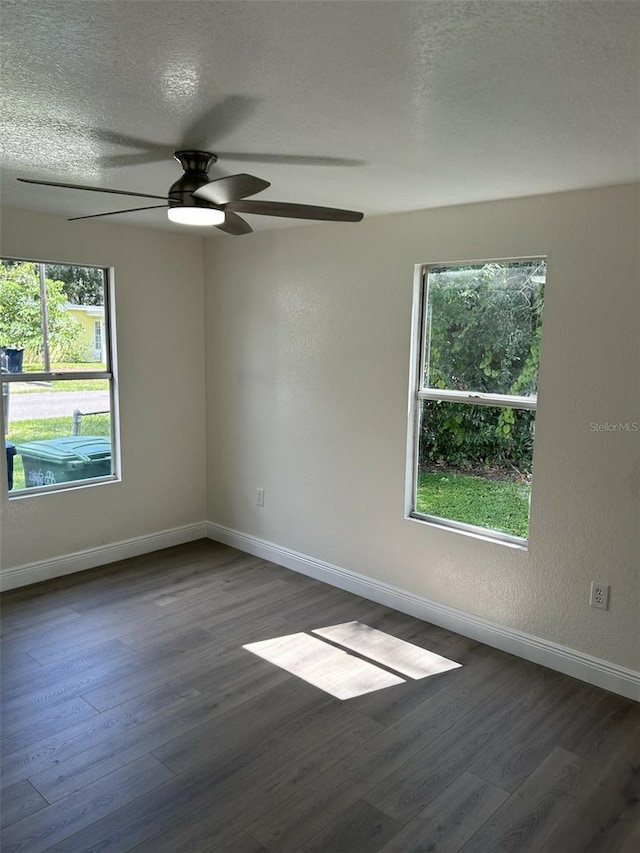 spare room featuring a healthy amount of sunlight, dark hardwood / wood-style floors, and ceiling fan