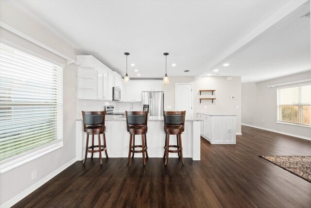 kitchen with appliances with stainless steel finishes, white cabinets, pendant lighting, and plenty of natural light