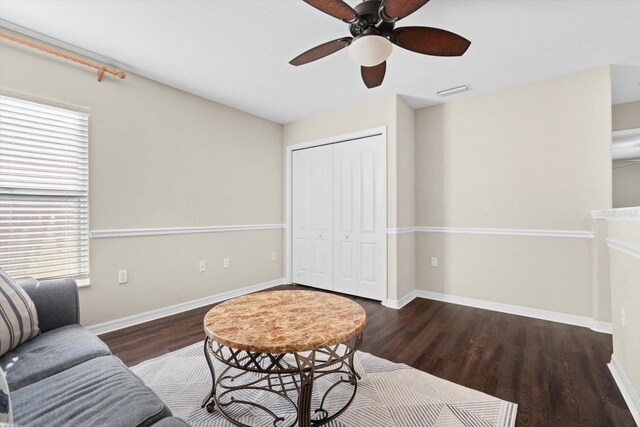 living room with dark wood-type flooring and ceiling fan