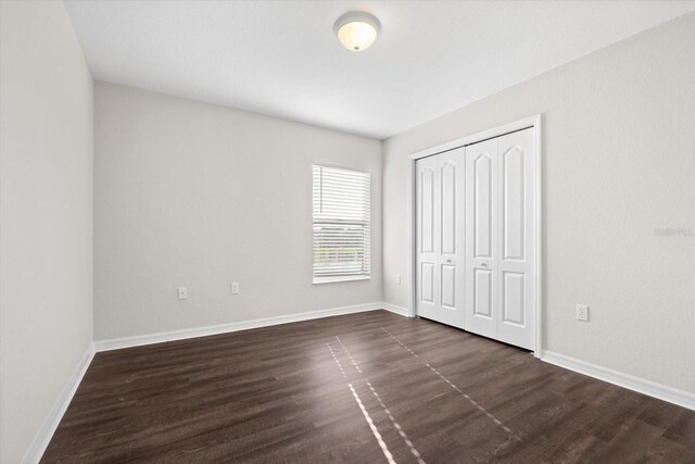 unfurnished bedroom with a closet and dark hardwood / wood-style flooring