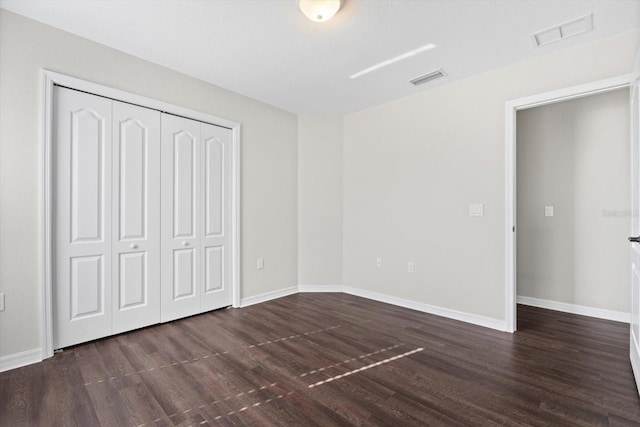 unfurnished bedroom featuring a closet and dark wood-type flooring