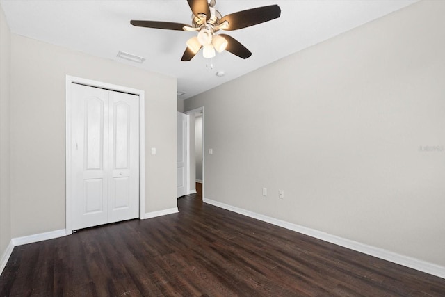 unfurnished bedroom featuring ceiling fan, a closet, and dark wood-type flooring