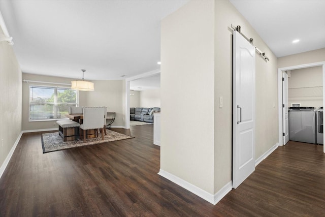 corridor with dark hardwood / wood-style floors, washer and dryer, and a barn door