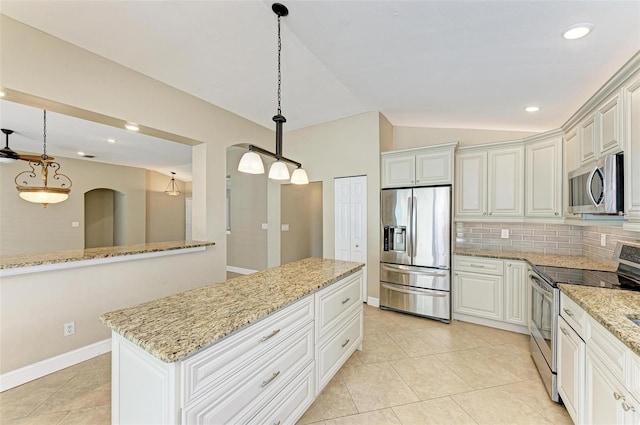 kitchen featuring light stone countertops, backsplash, pendant lighting, lofted ceiling, and appliances with stainless steel finishes