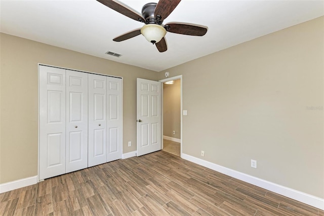 unfurnished bedroom featuring hardwood / wood-style flooring, ceiling fan, and a closet