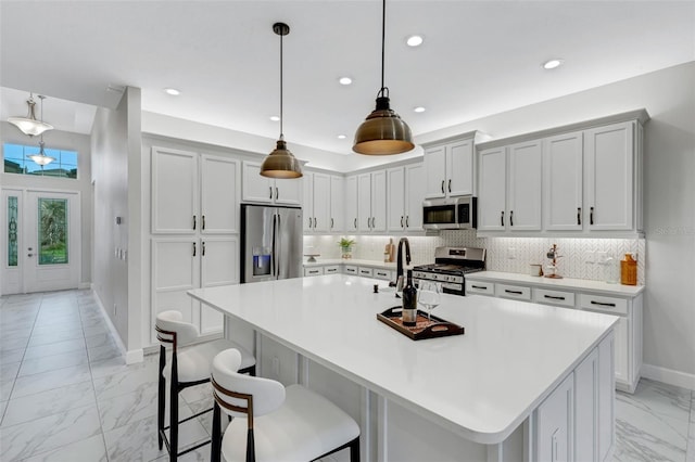 kitchen featuring a large island with sink, appliances with stainless steel finishes, a kitchen bar, pendant lighting, and decorative backsplash