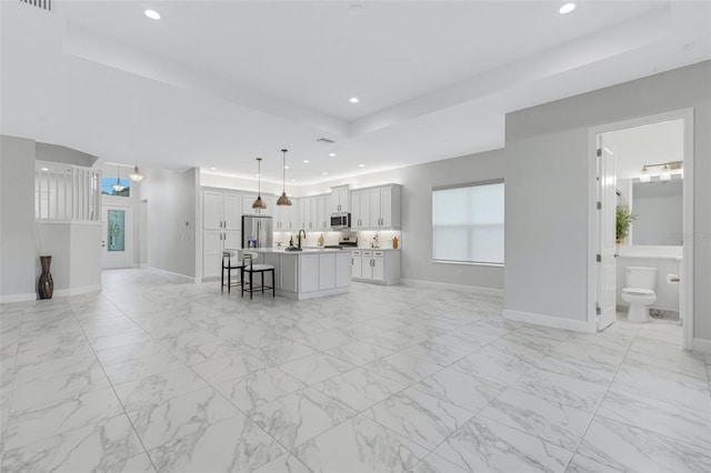 unfurnished living room featuring sink and a raised ceiling