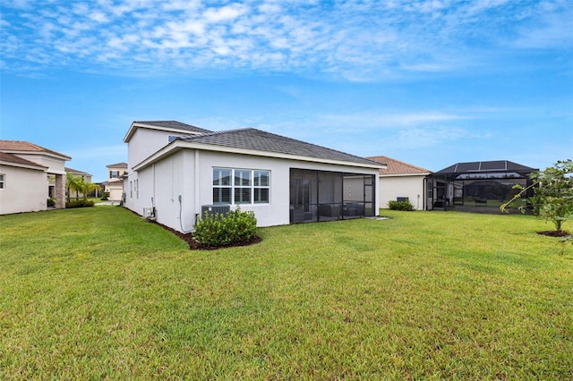 rear view of house featuring a sunroom and a lawn